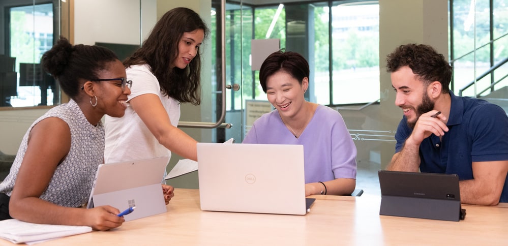 Graduate students collaborating while looking at a laptop